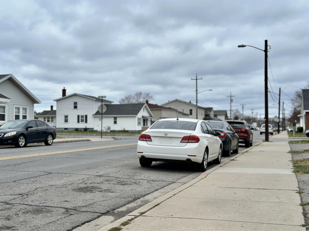 AI photo edit — after: the same residential street with the power lines and the green trash bin removed